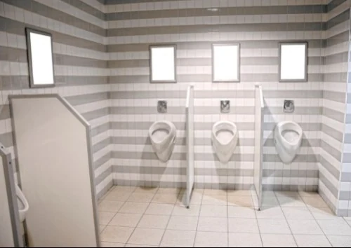 Helle Urinaltrennwände der Serie TF in einem gefliesten Sanitärraum